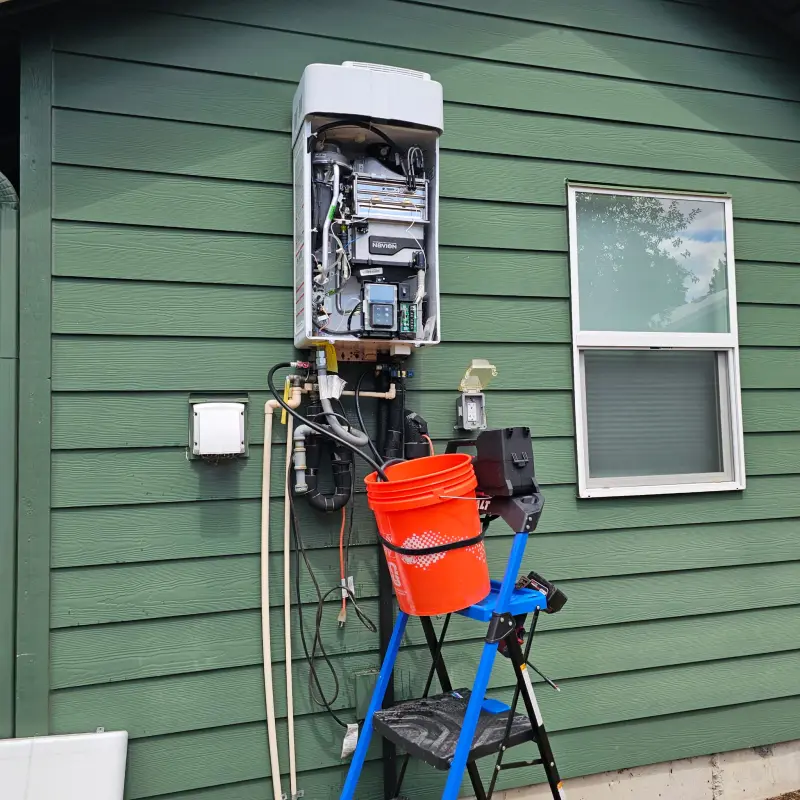 Exterior wall-mounted Navien tankless water heater opened up for service