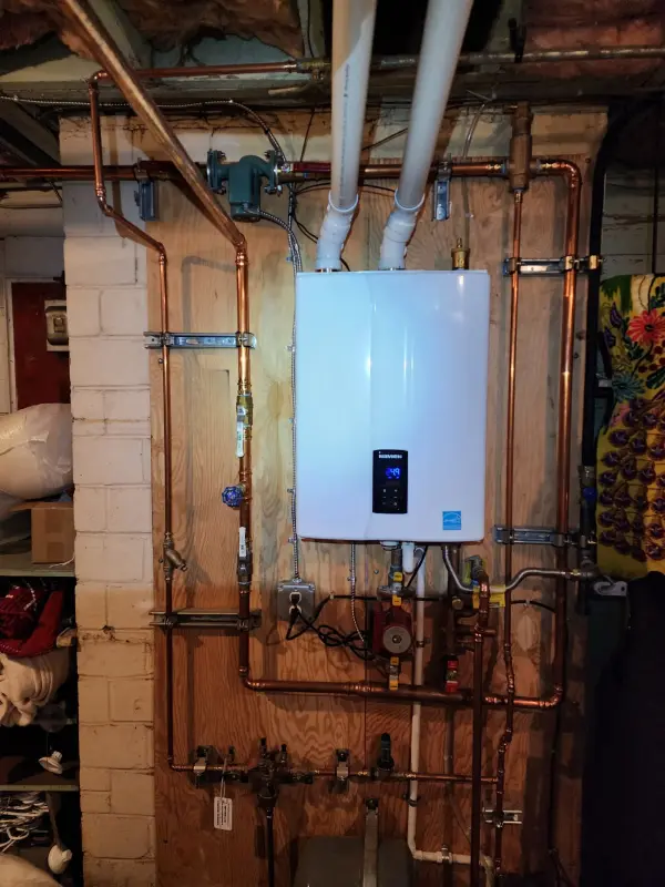 Navien tankless water heater mounted in a basement with a new copper manifold and recirculation pump