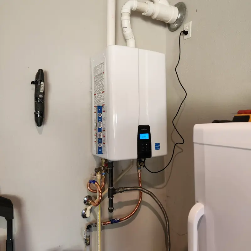 Navien tankless water heater installed in a narrow utility closet with a level held against it
